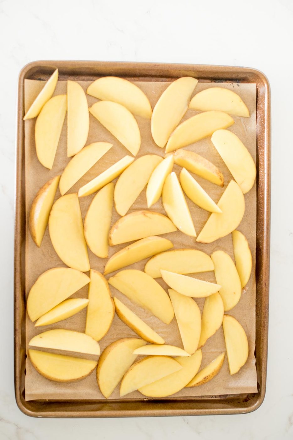 cut potato wedges on a parchment lined baking sheet