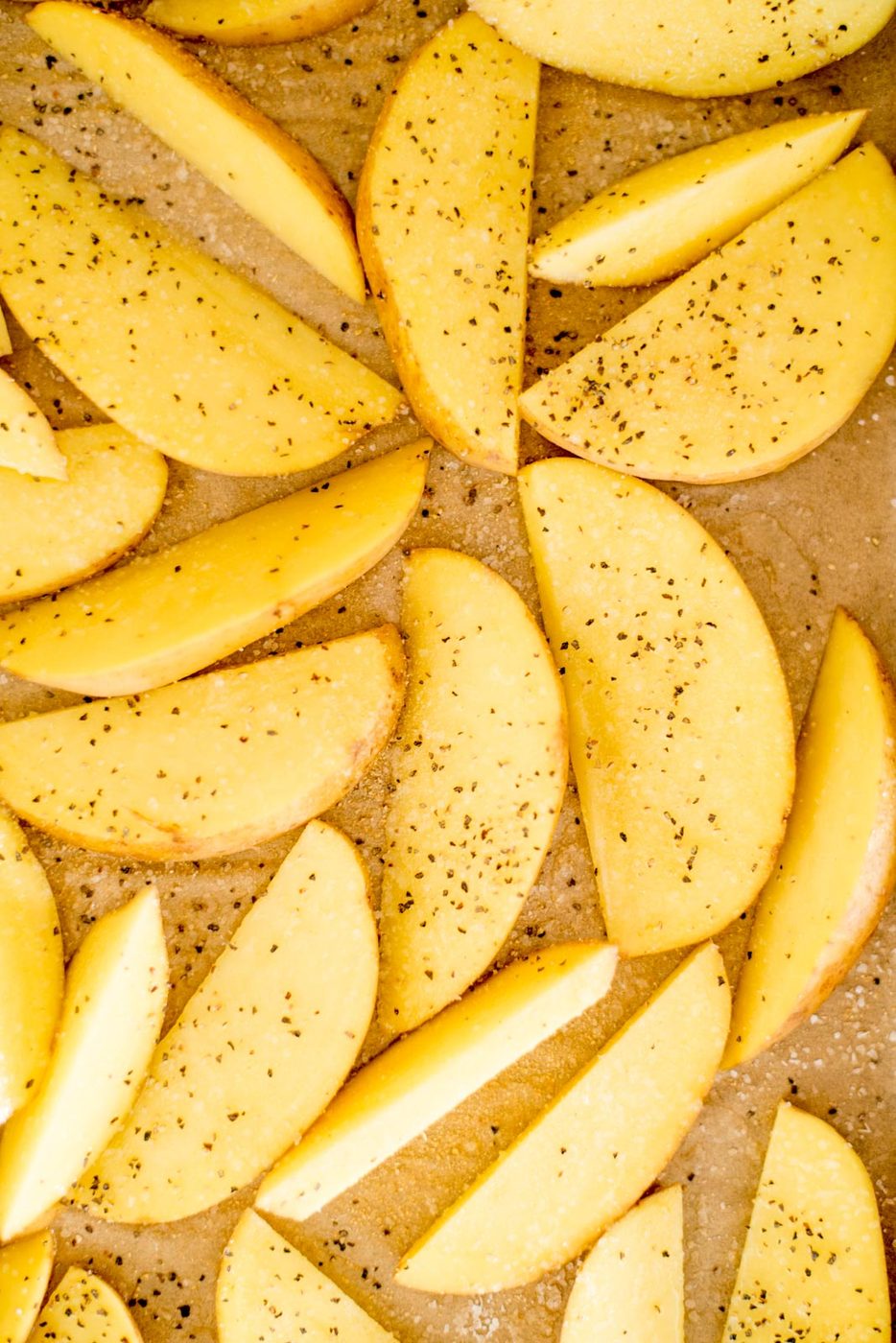 seasoned potato wedges on a parchment lined baking sheet