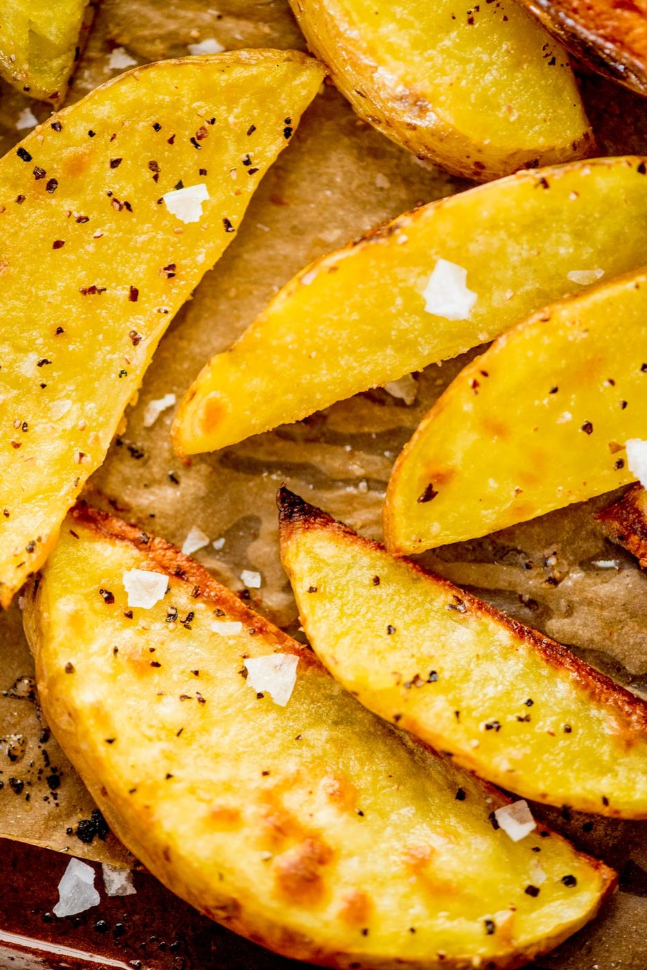 crispy oven baked garlic potato wedges with flaky sea salt on a baking sheet