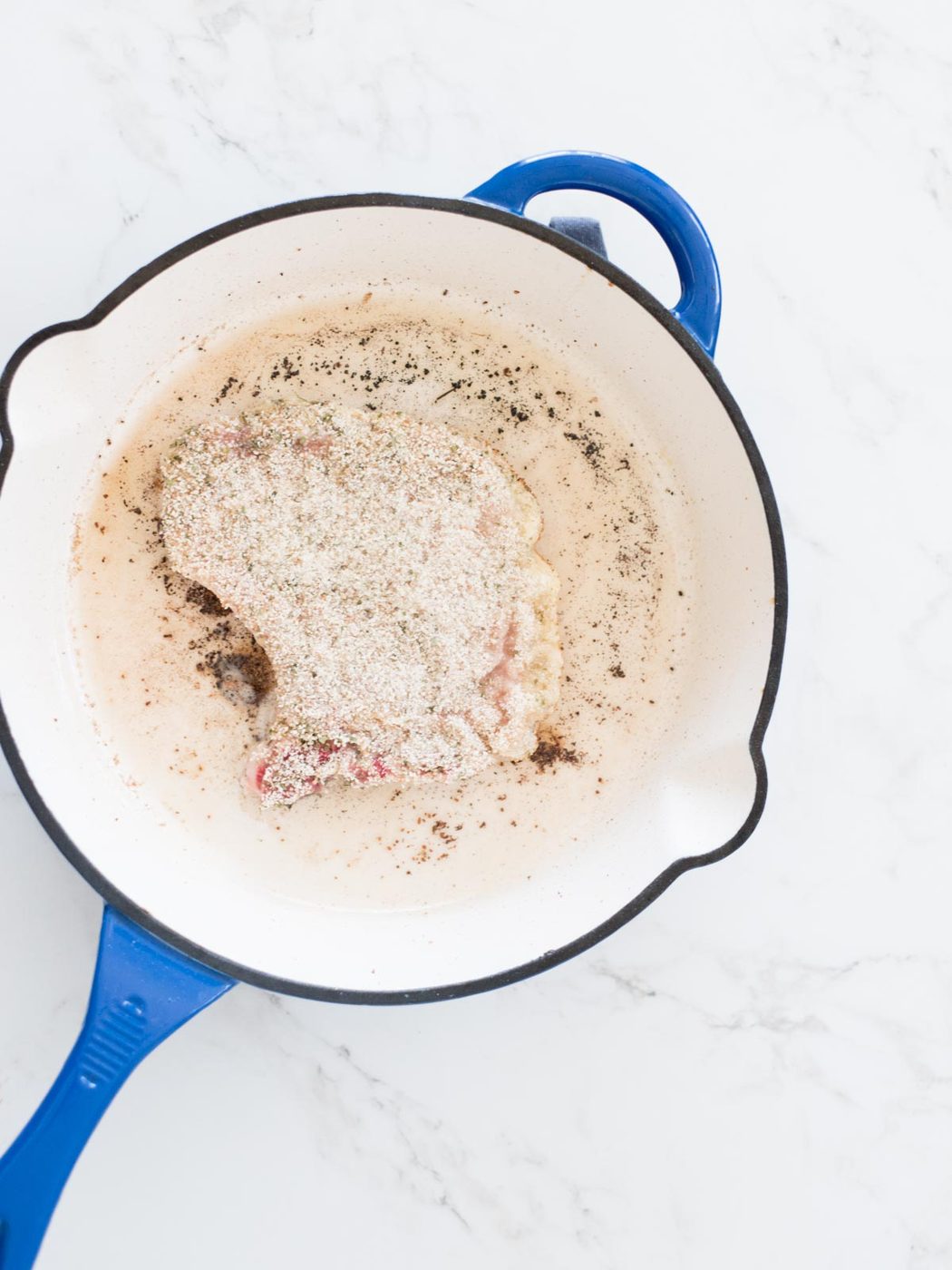 breaded pork chop frying in a skillet