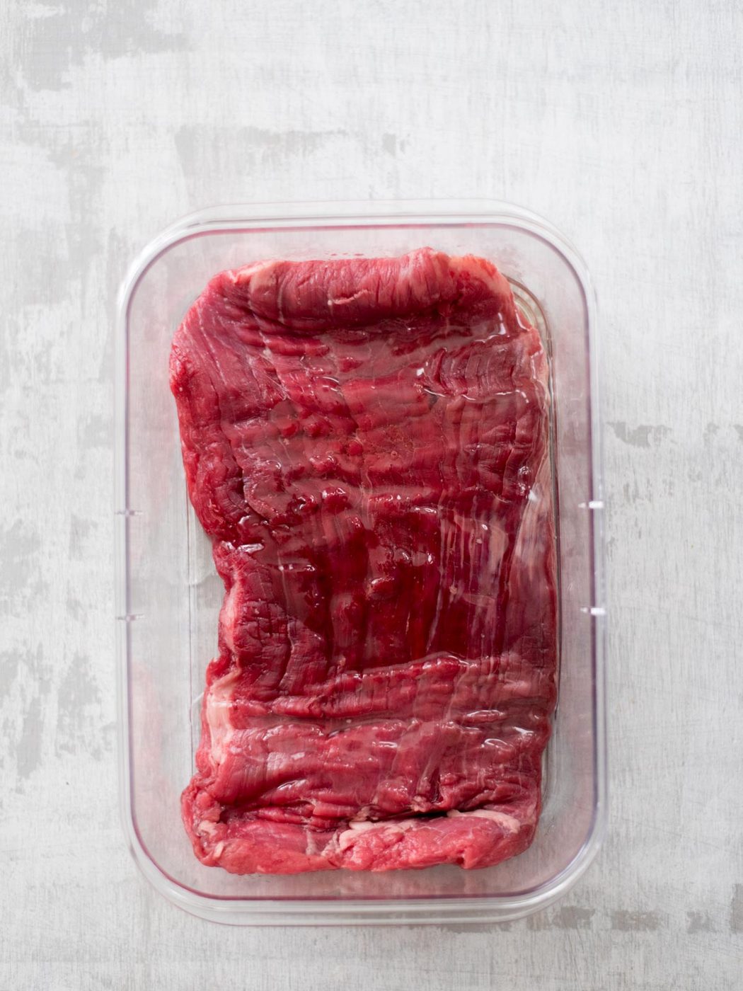 oil added to flank steak in container
