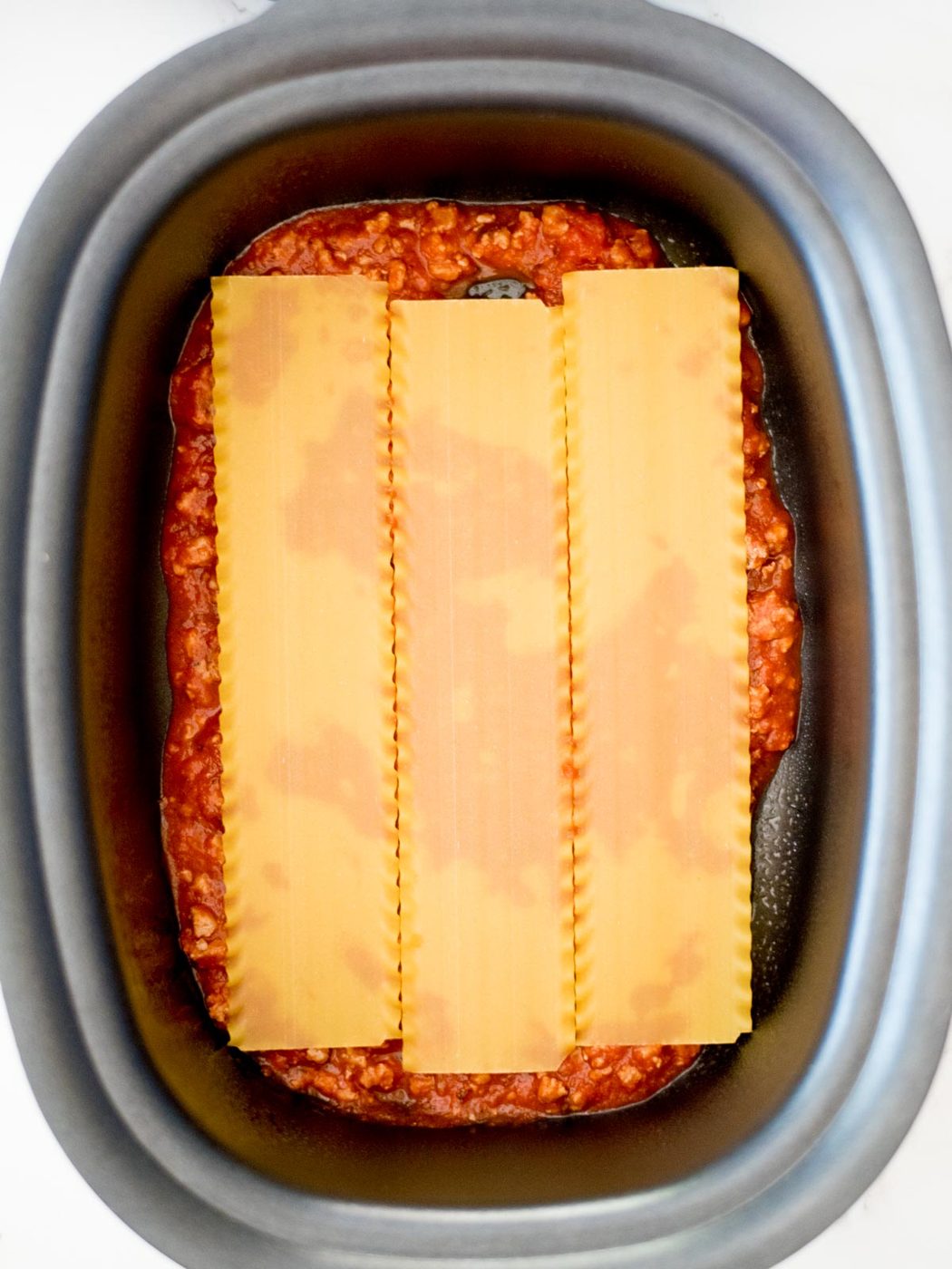 noodles on top of sauce in the crockpot