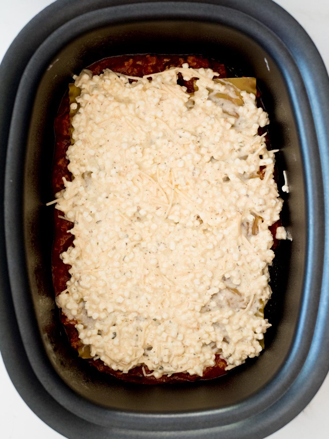 cheese mixture on top of noodles in the crockpot