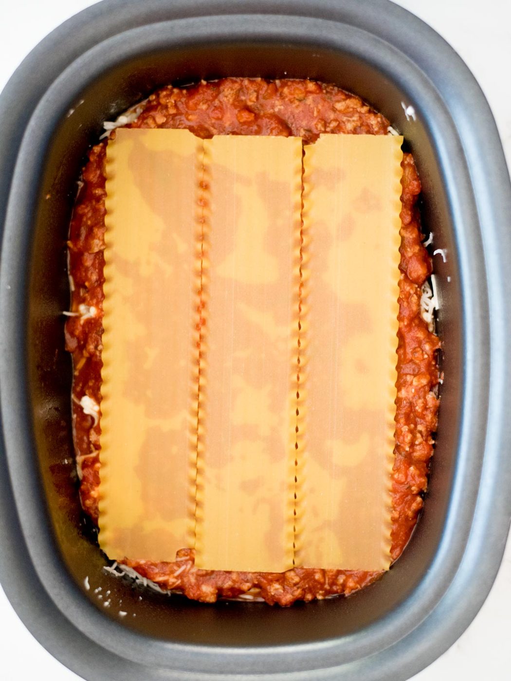 noodles on top of sauce in the crockpot