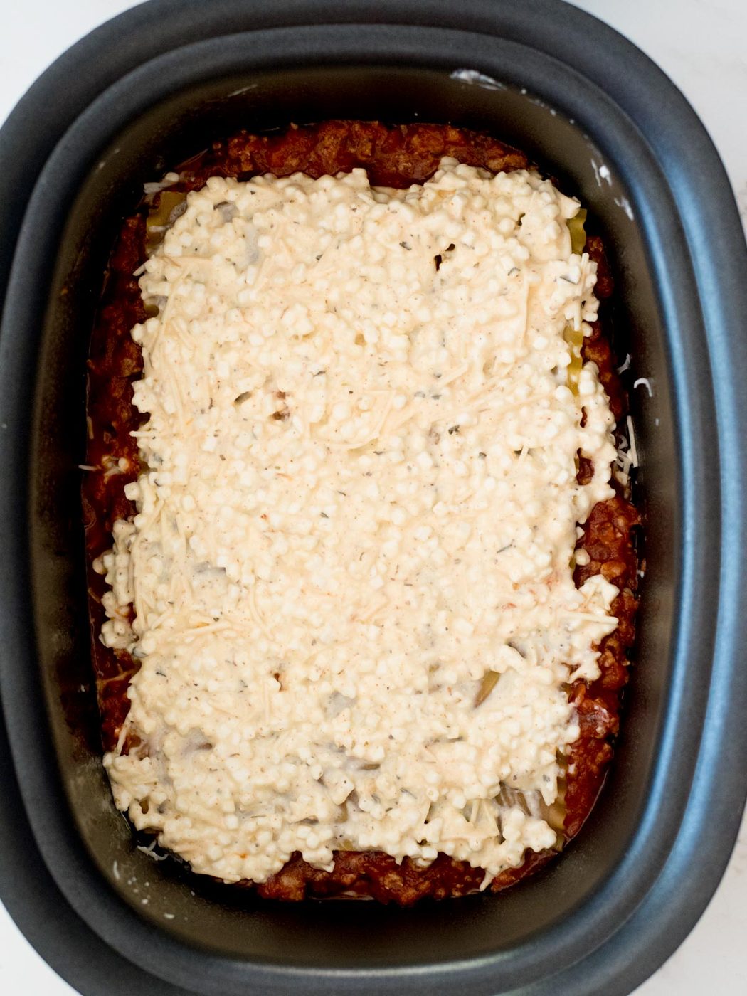 cheese mixture on top of noodles in the crockpot