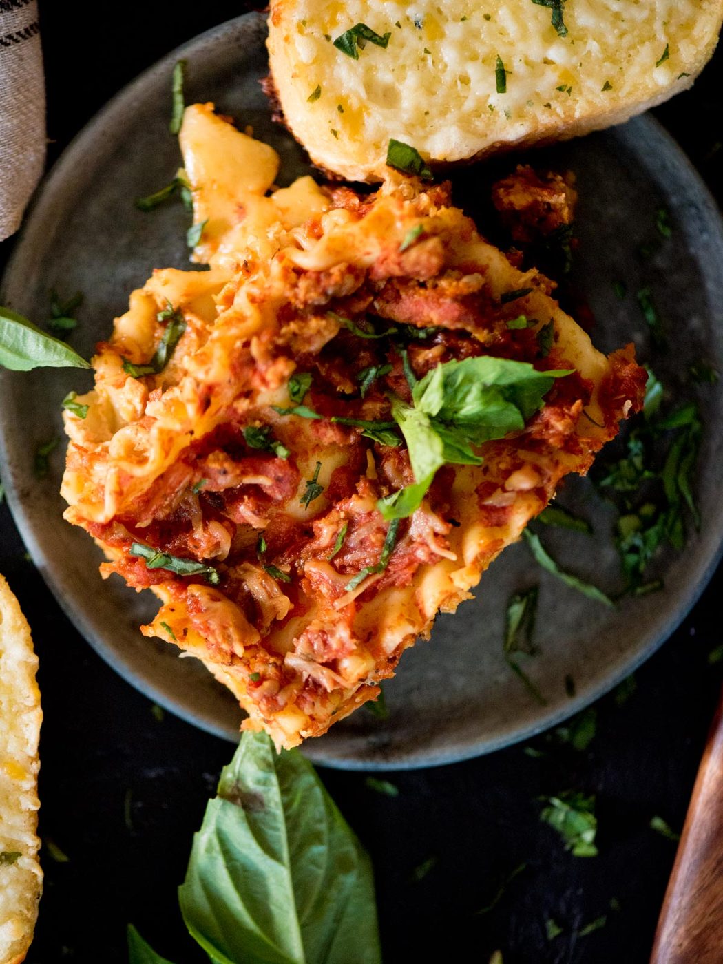 crockpot lasagna topped with fresh basil and a slice of garlic bread