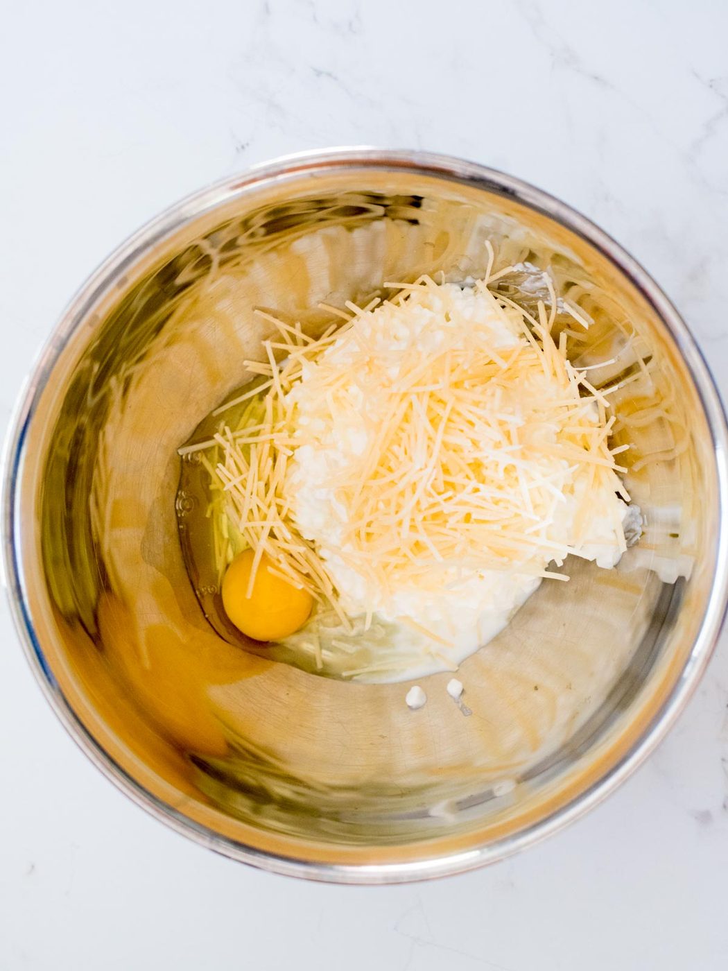 egg added to cottage cheese and parmesan in a mixing bowl
