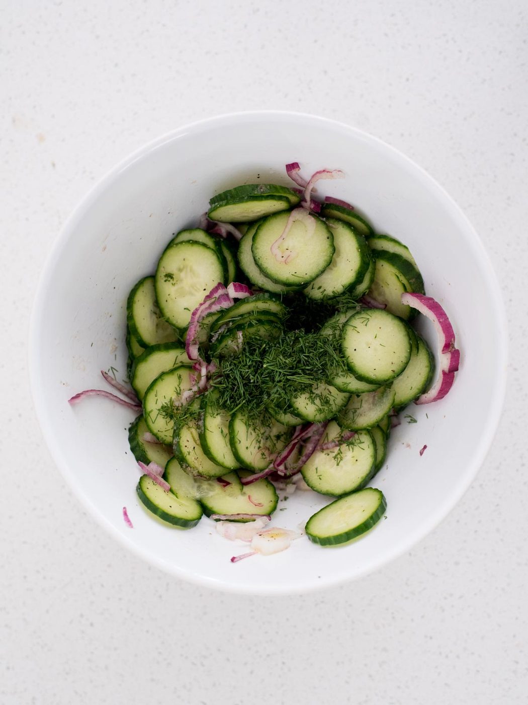 fresh dill added to the mixing bowl with onions and cucumbers