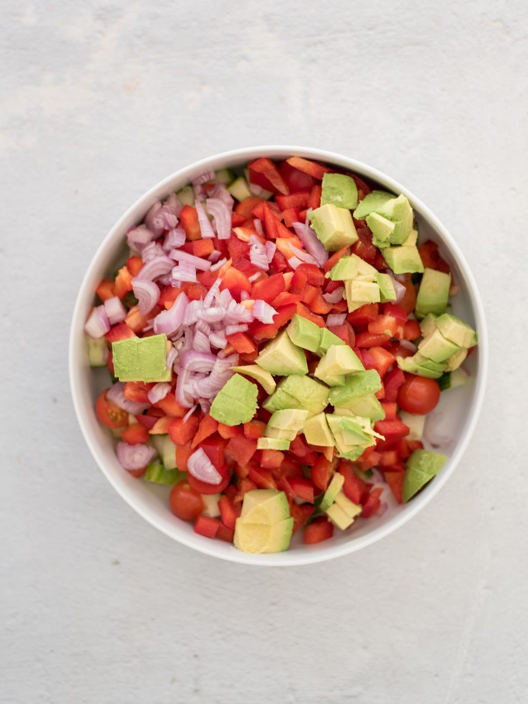 Chopped ingredients for cucumber tomato salad in a bowl before combining.