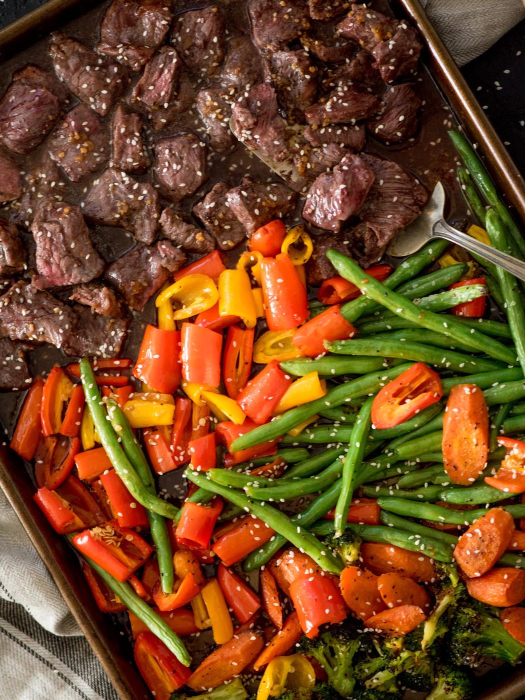 straightforward sheet pan beef teriyaki cooked on a baking sheet with a serving spoon
