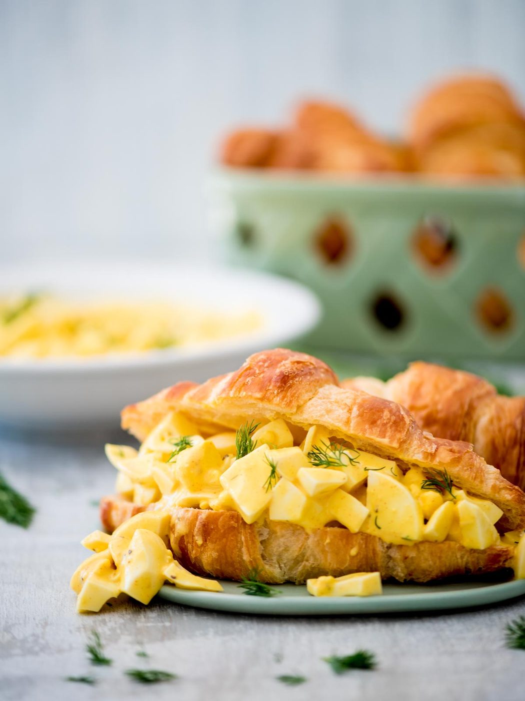 classic egg salad sandwich on a croissant with fresh dill