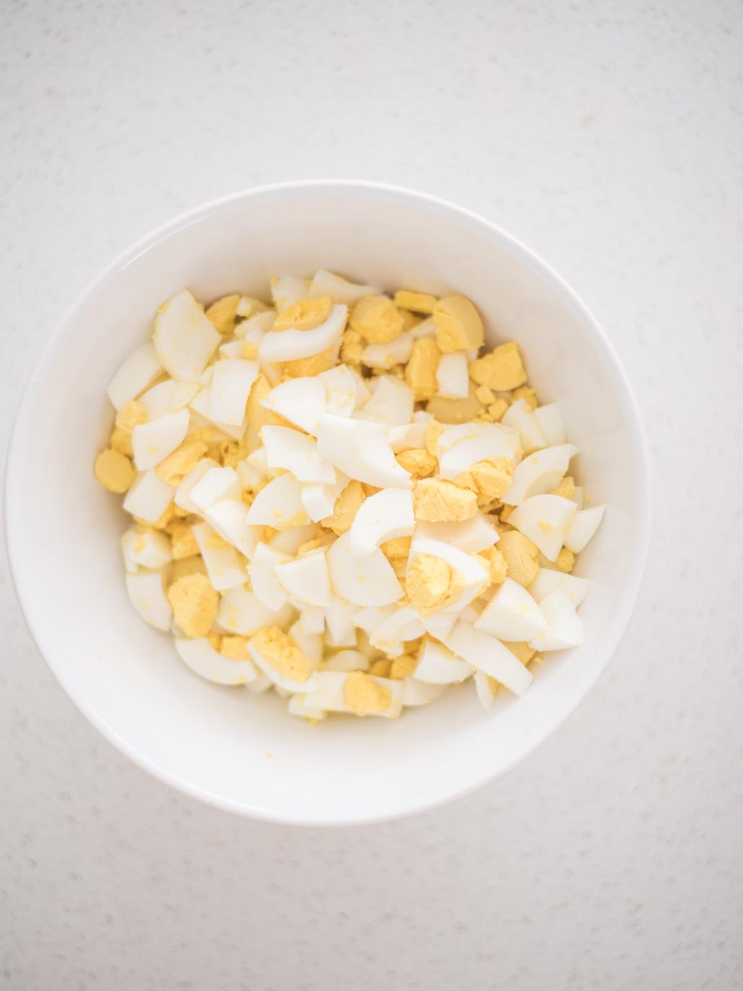 chopped hard boiled eggs in a mixing bowl to begin making an straightforward egg salad recipe