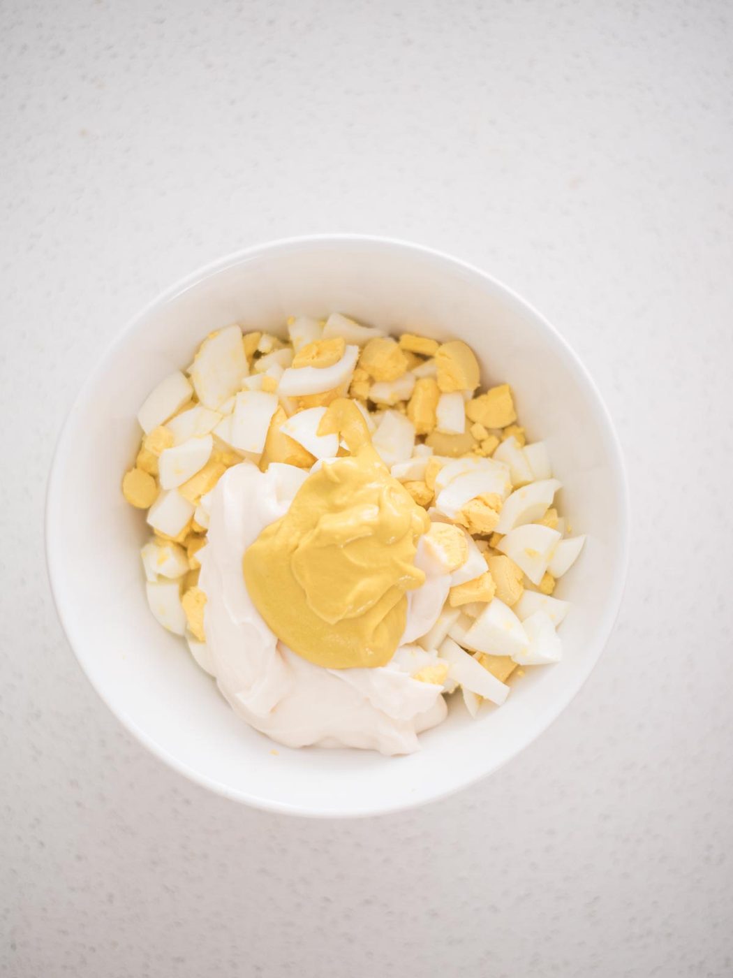 mustard added to the mayo and eggs in a mixing bowl to make egg salad