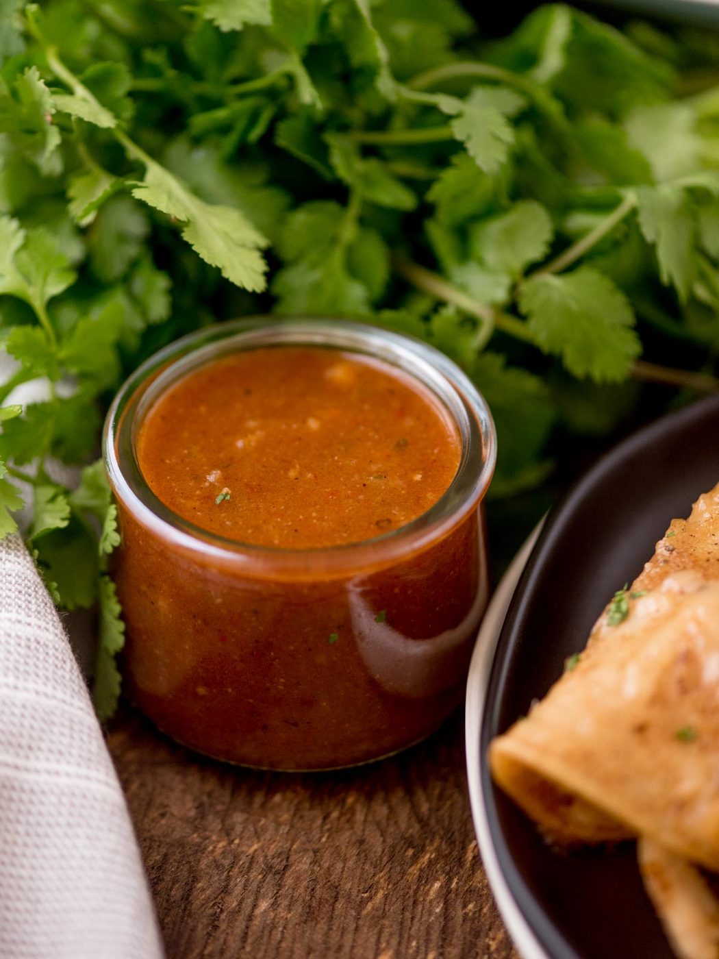 Enchilada sauce in a jar with cilantro bunch in the background
