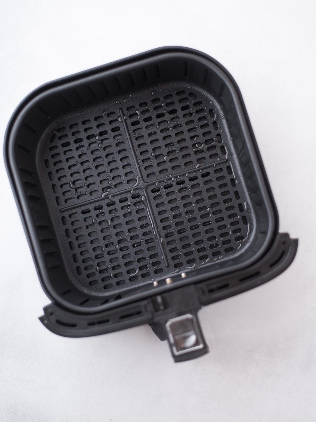 Avocado oil spray over the air fryer bucket.