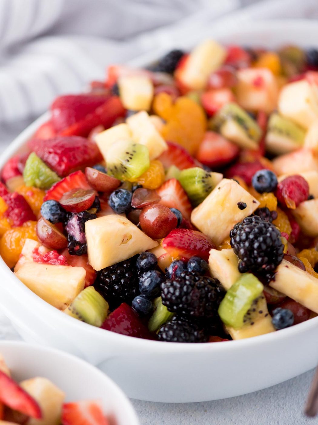fruit salad with dressing in a white bowl with a serving utensil