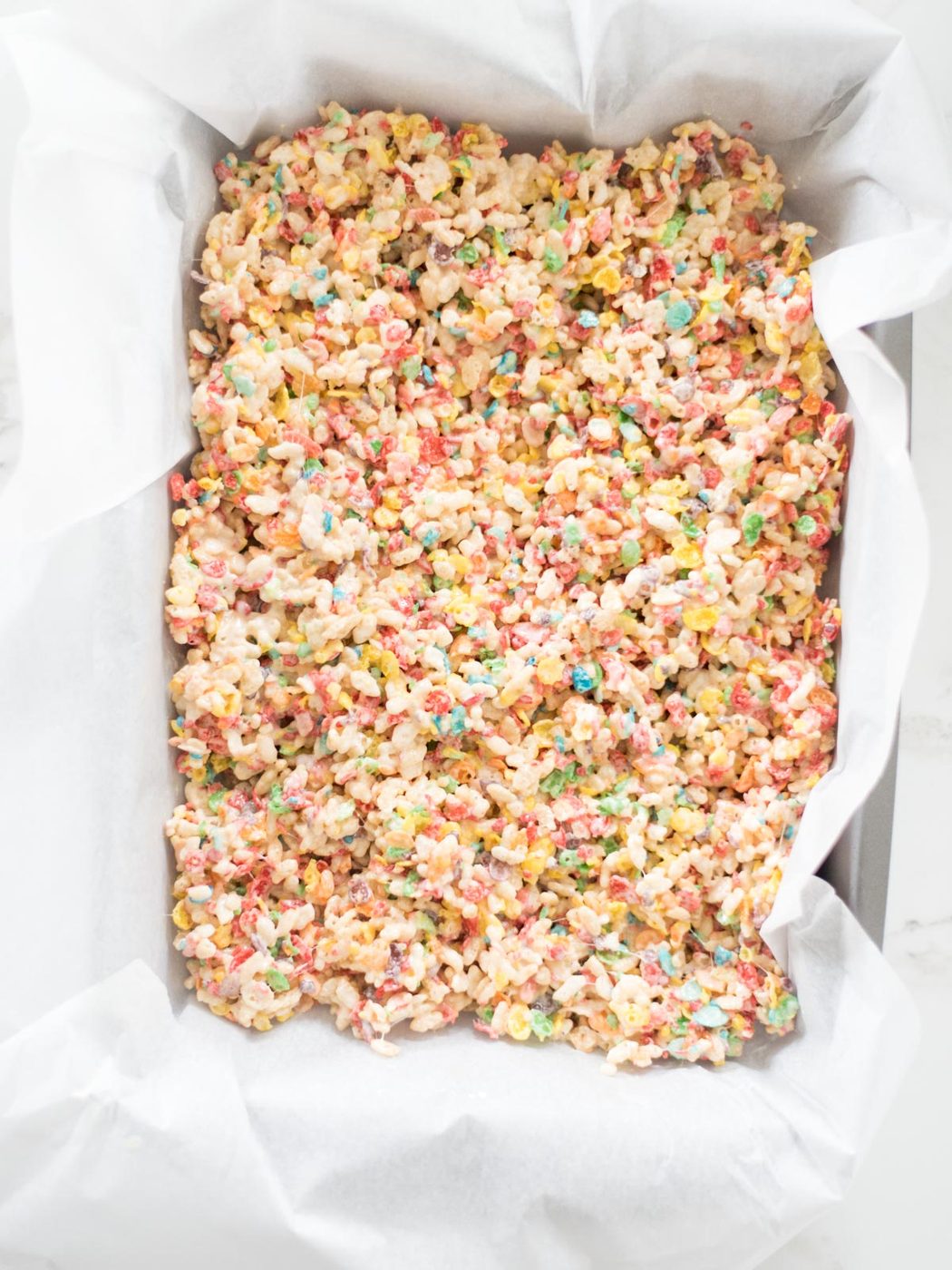 fruity pebbles rice krispie treats smoothed into a 9x13 pan