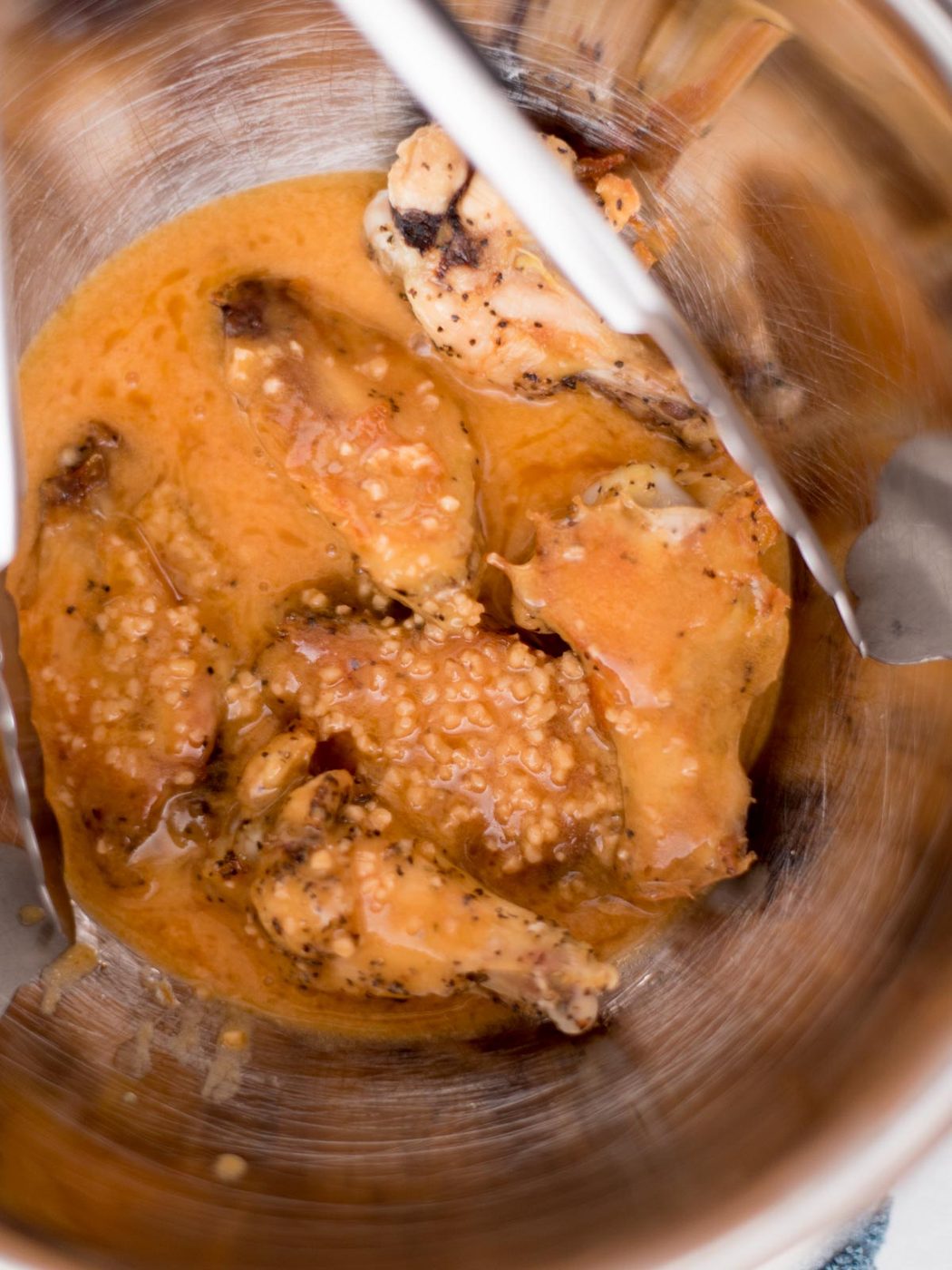 cooked wings in a mixing bowl with garlic butter sauce
