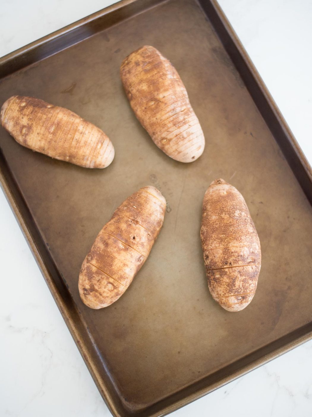 sliced hasselback potatoes on a baking sheet
