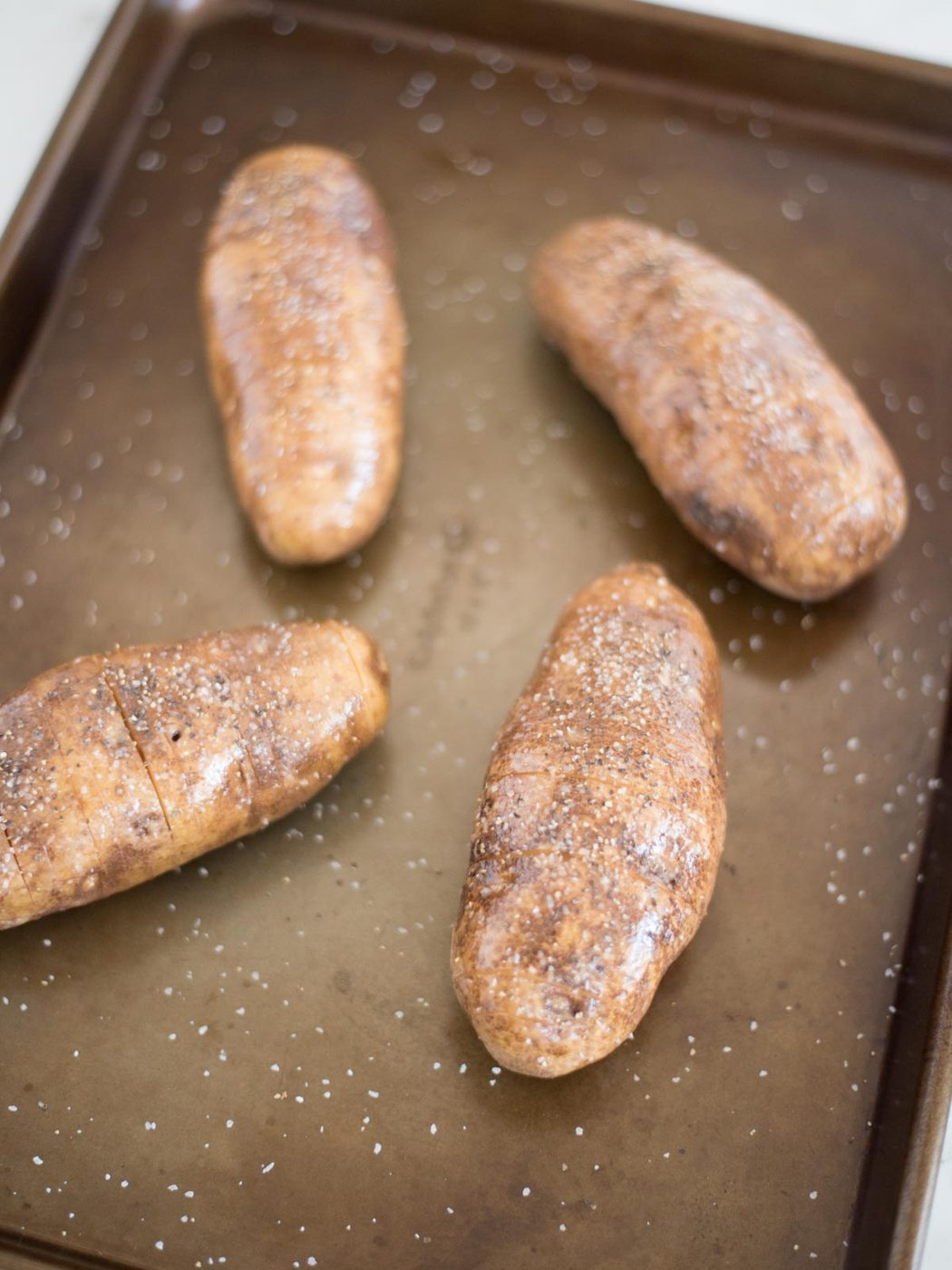 salt, pepper, and butter on a sliced hasselback potato