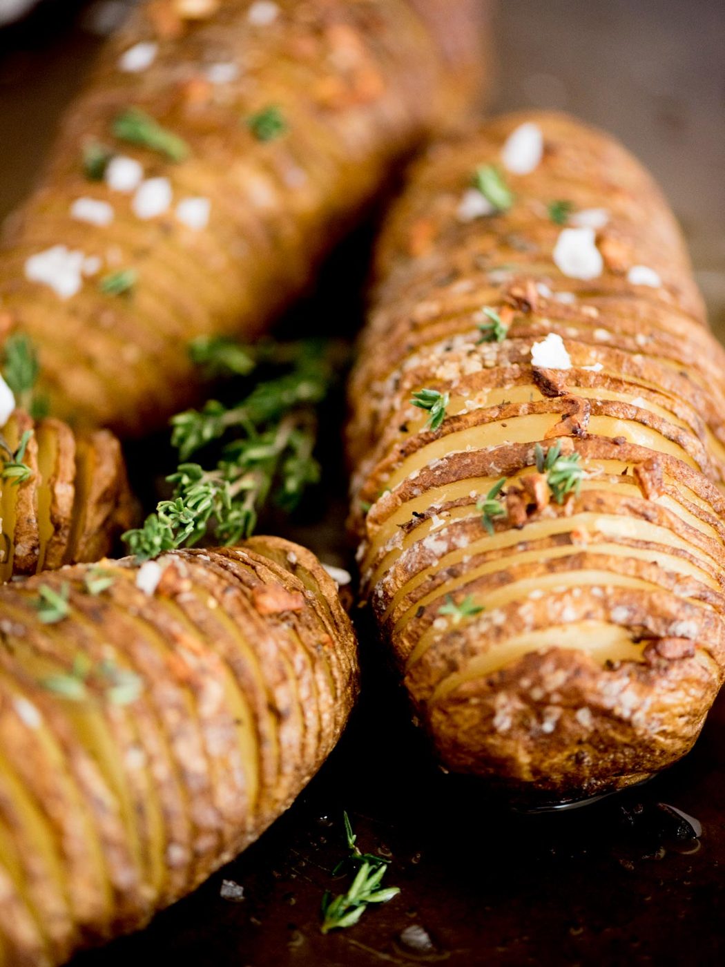 garlic butter hasselback potatoes topped with fresh thyme and flaked salt