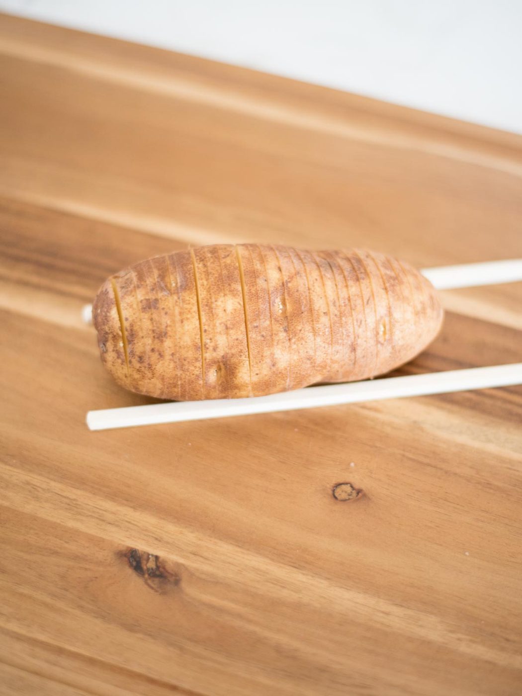 sliced hasselback potato on chopsticks