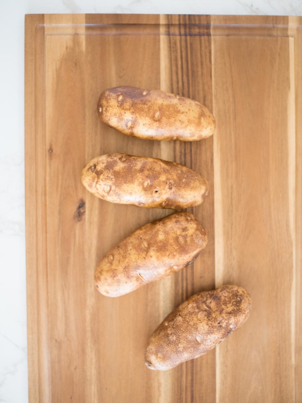 washed russet potatoes on a cutting board