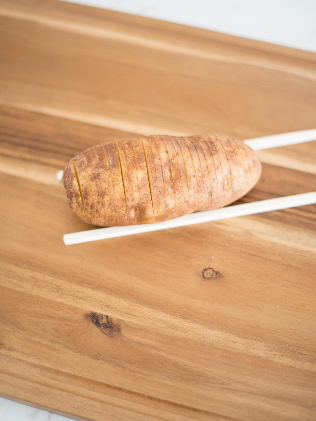 sliced hasselback potato on chopsticks