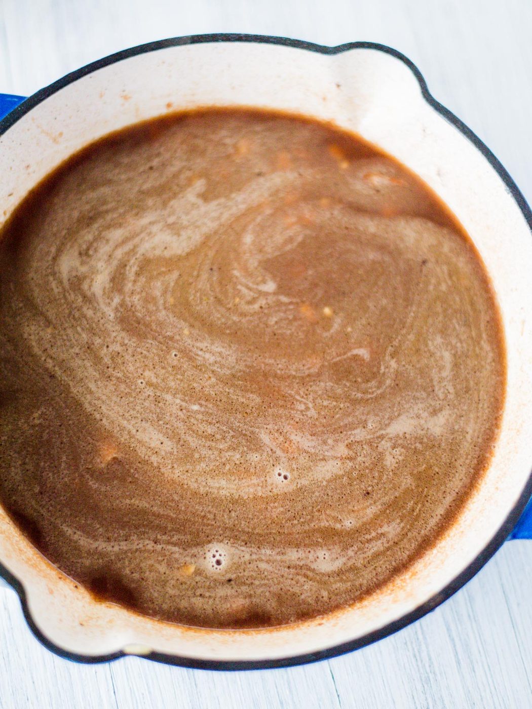 vegetable broth poured into a skillet over orzo