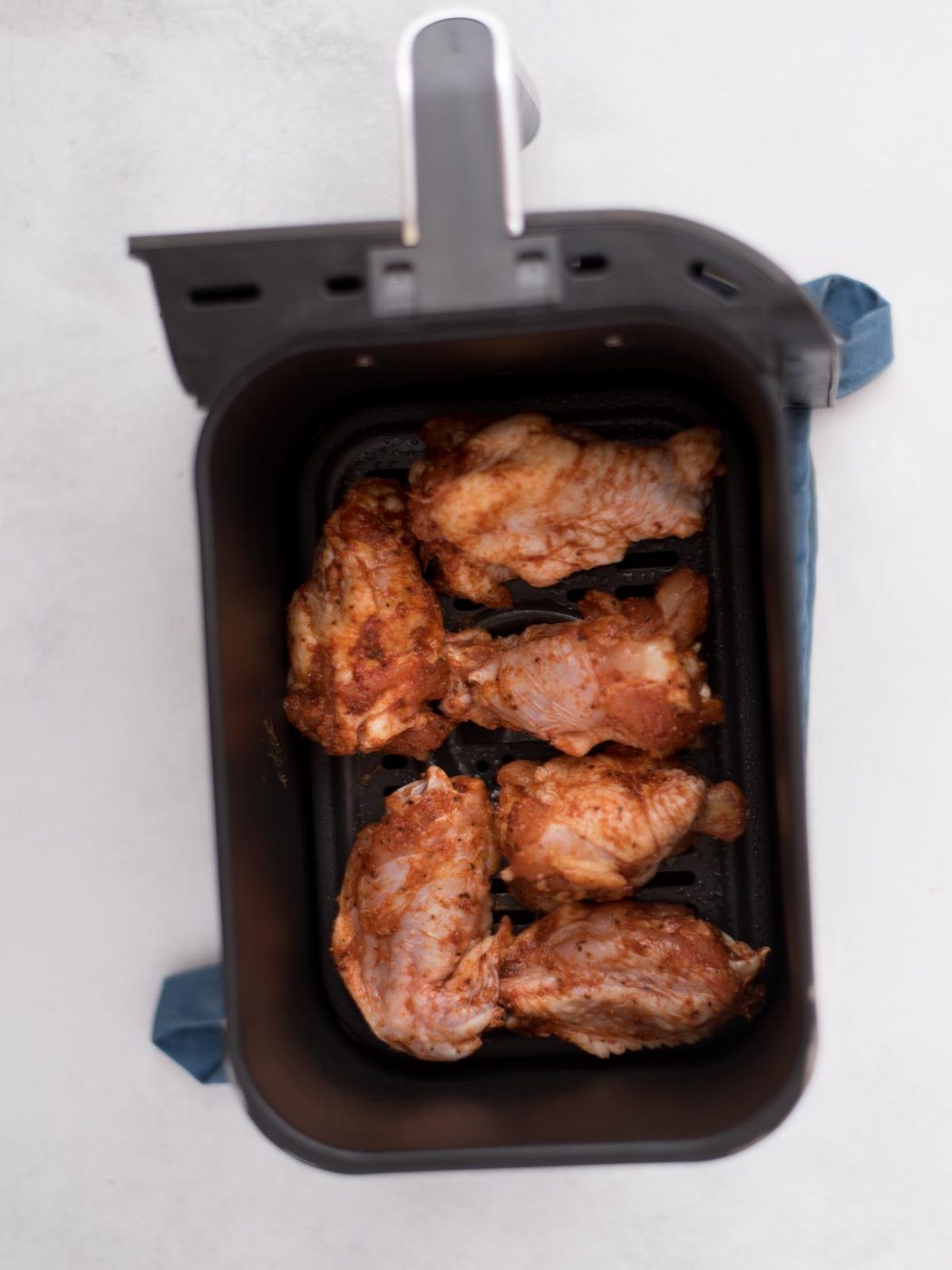 seasoned wings inside of an air fryer basket