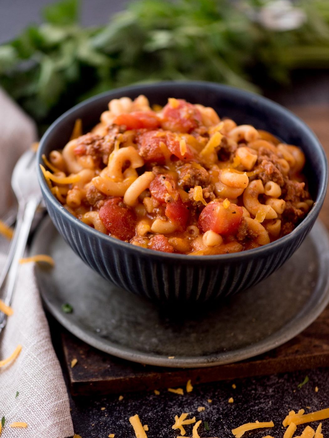 american goulash in a bowl topped with shredded cheddar cheese