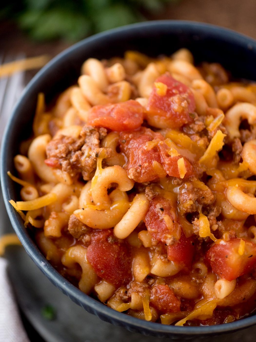 american goulash in a bowl topped with cheese