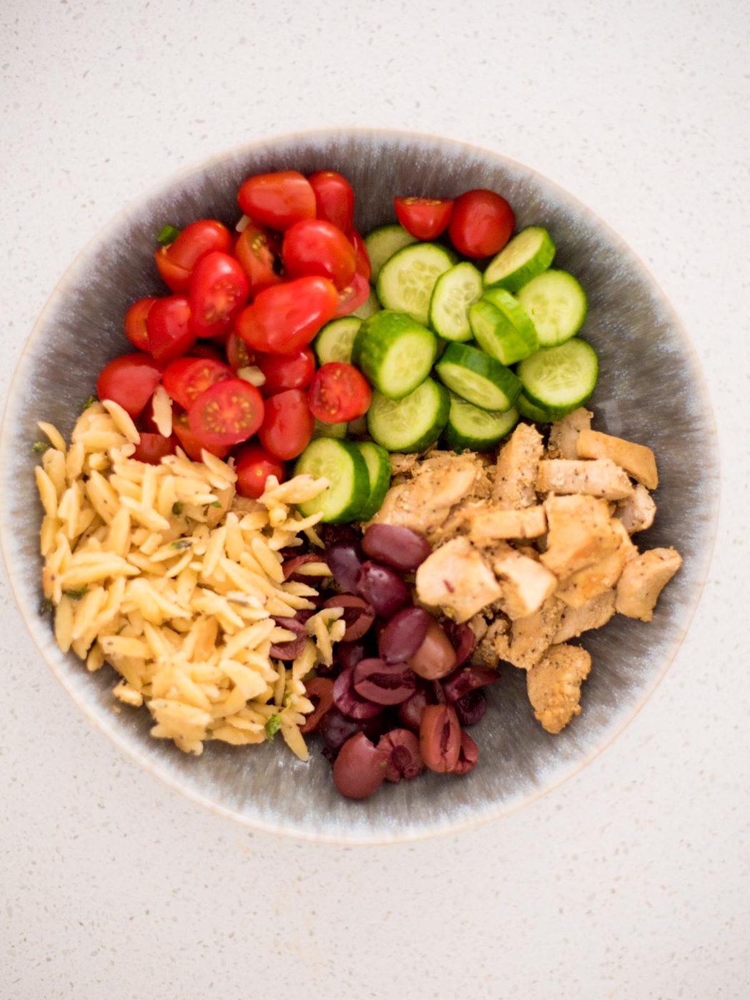assembly of a greek chicken bowl without tzatziki