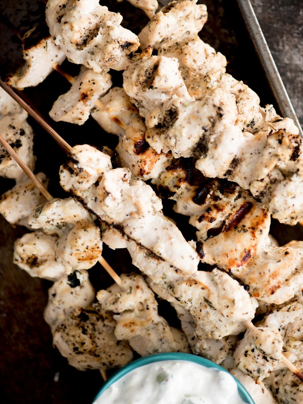 greek grilled chicken skewers stacked together with tzatziki sauce