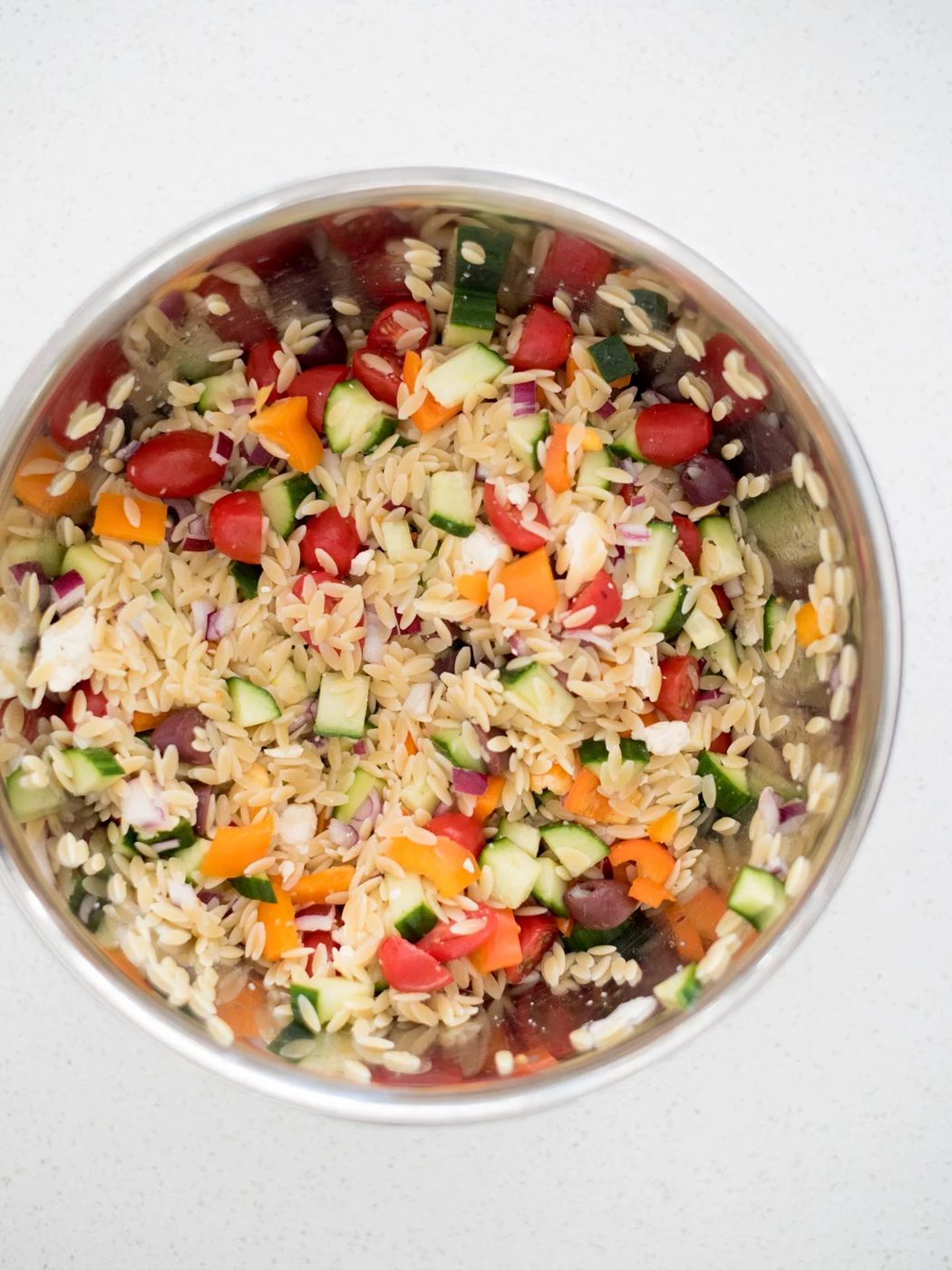 vegetables combined with cooked orzo in a large mixing bowl