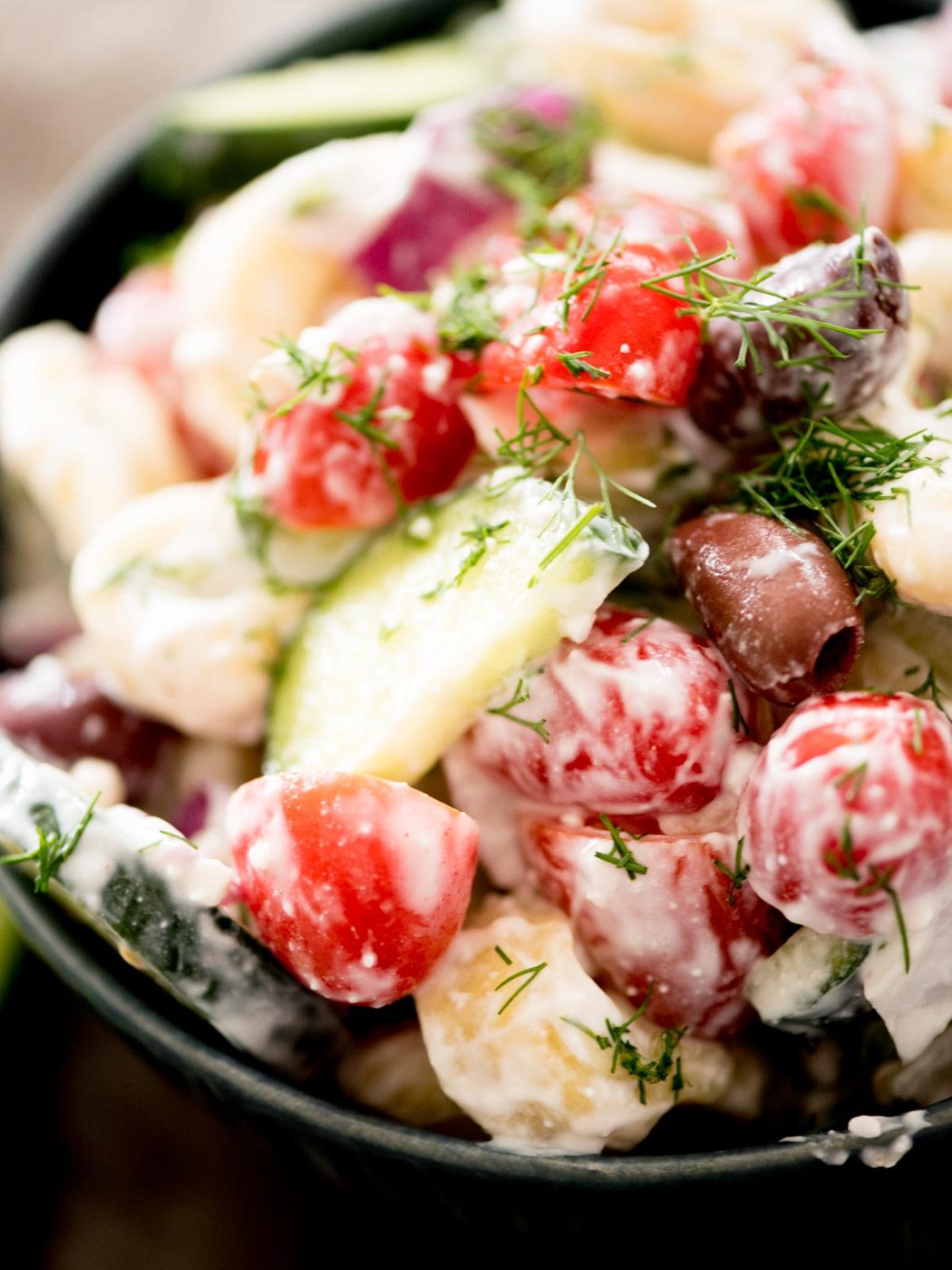 greek pasta salad in a bowl topped with fresh dill