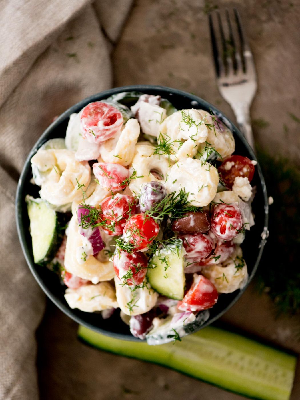 greek pasta salad in a bowl topped with fresh dill