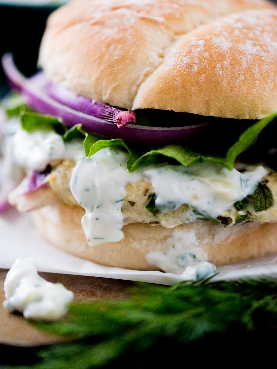 greek turkey burger in a bun topped with tzatziki sauce, red onion, and lettuce