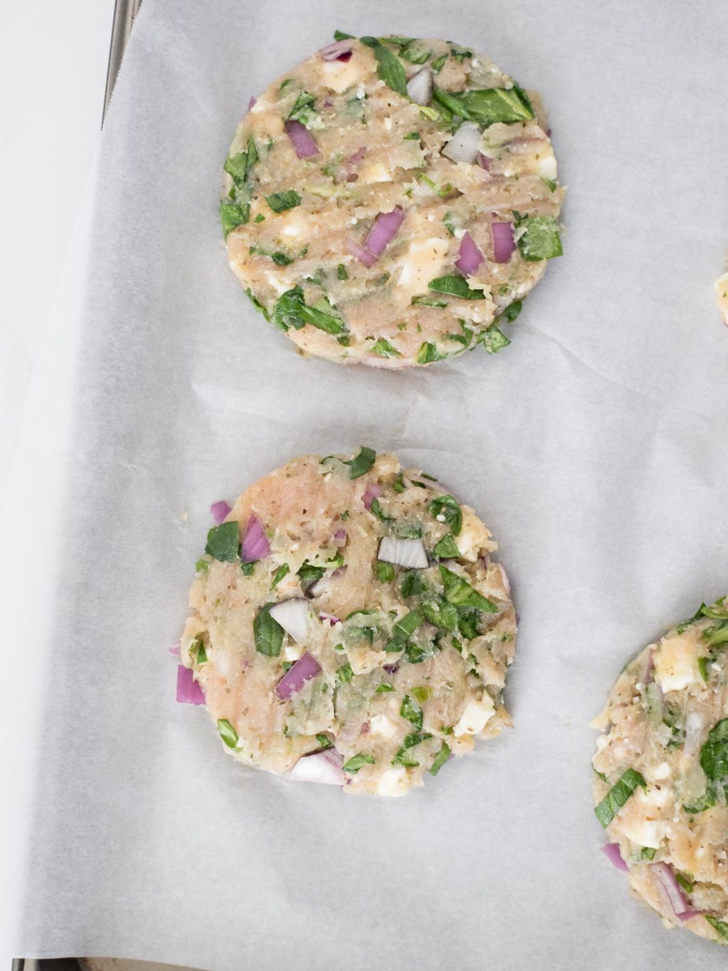 raw turkey burger patties on parchment paper