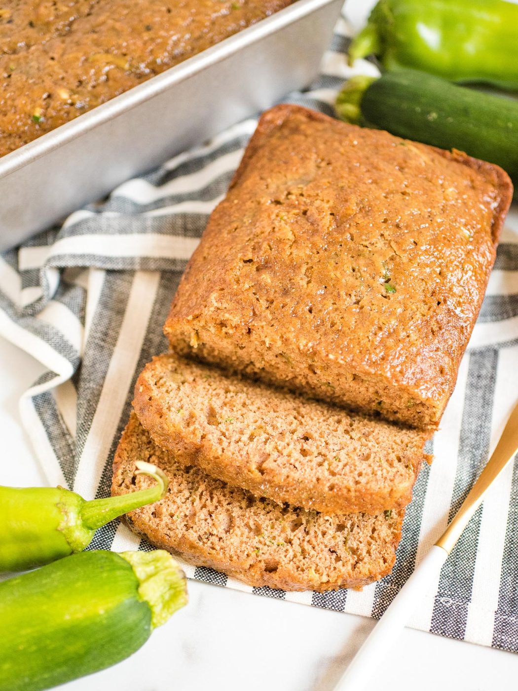 sliced loaf of green chile zucchini bread on a striped cloth