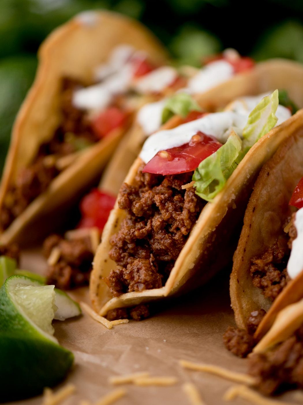 ground beef tacos on parchment paper surrounded by cilantro and limes