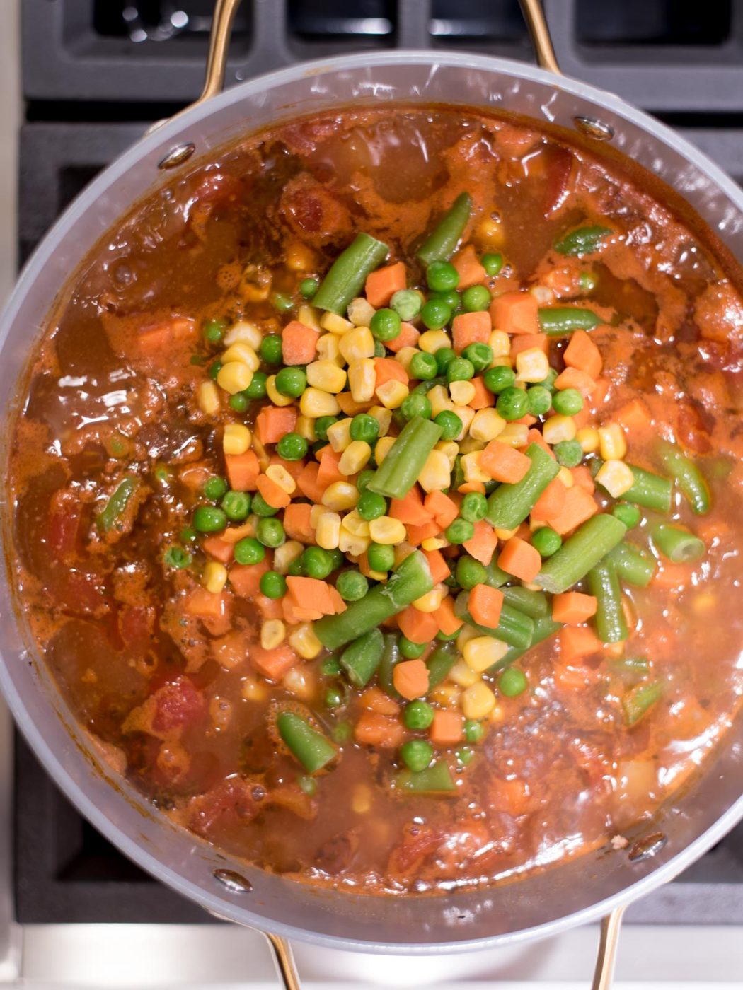 hamburger soup in a pot on the stove before the vegetables have been stirred in.