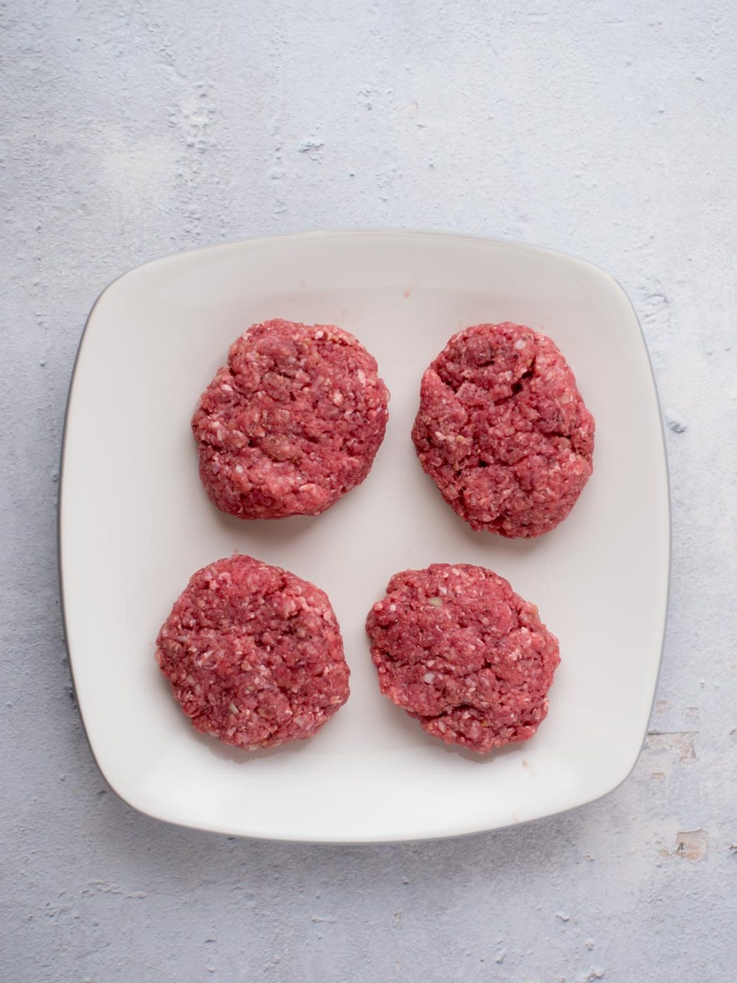 seasoned hamburger patties on a plate