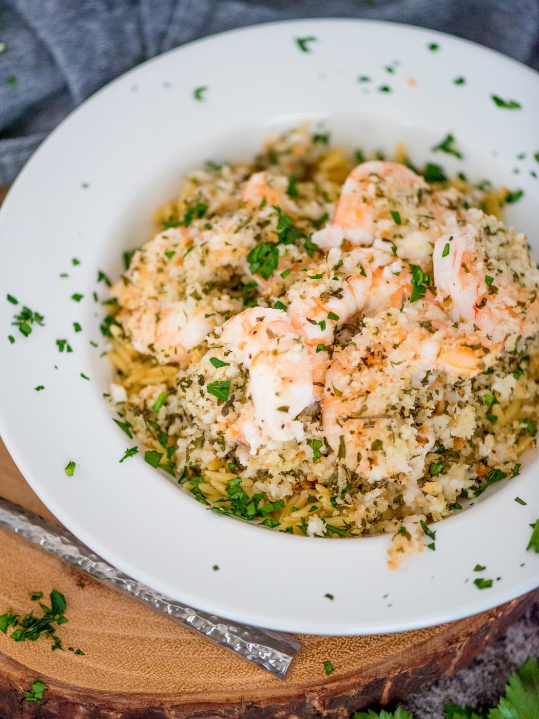 baked shrimp scampi with crispy panko topping served over orzo pasta and garnished with parsley