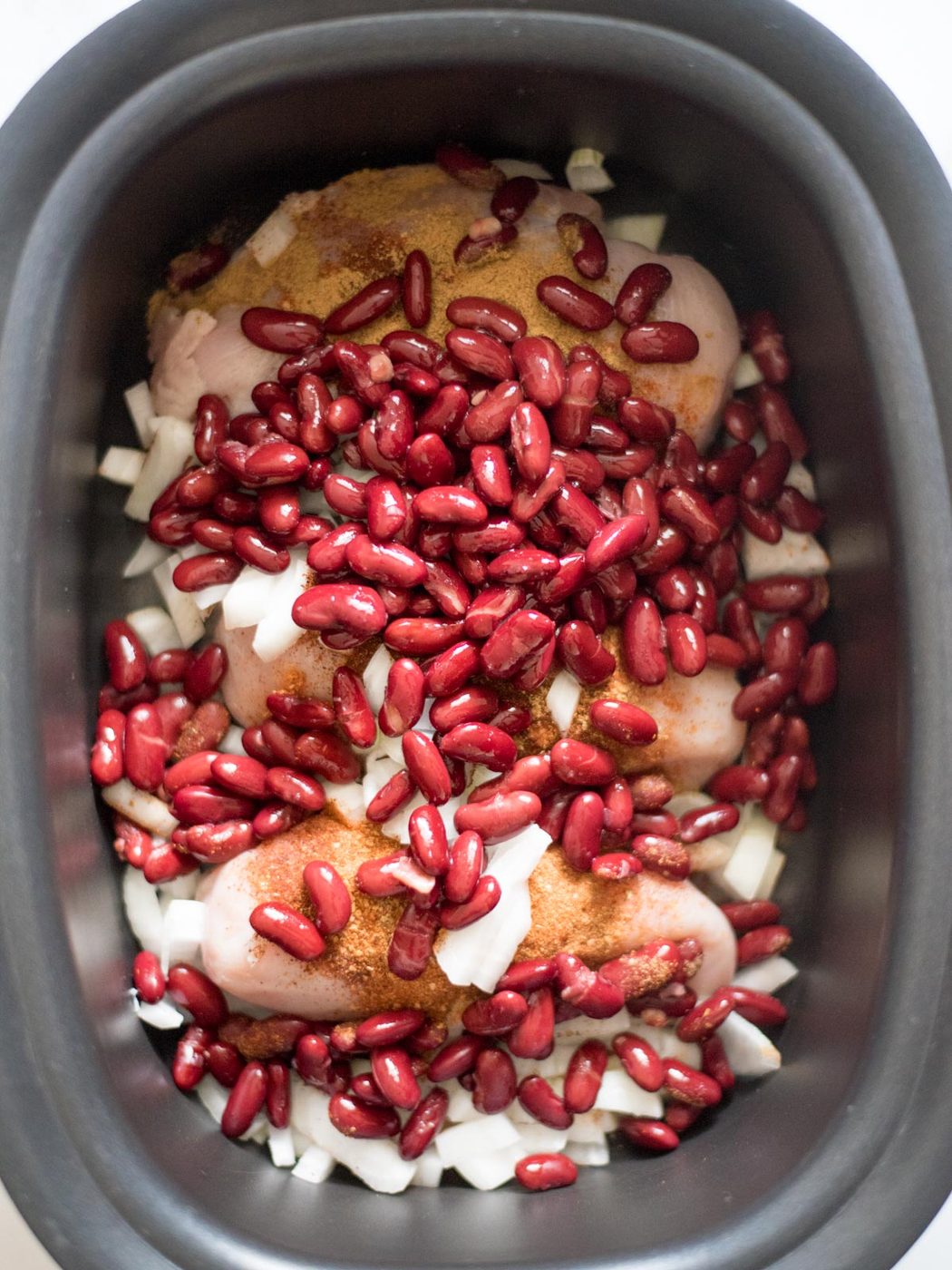 beans added to crockpot with seasoned chicken and onions