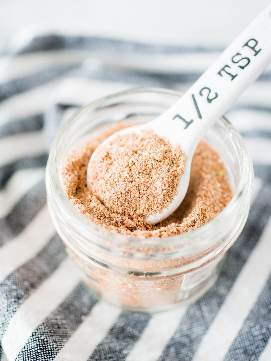 from-scratch taco seasoning in a jar with a measuring spoon