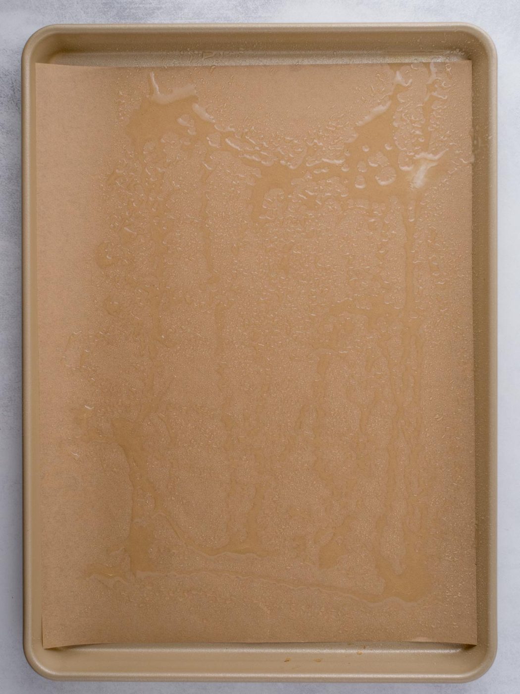 Avocado oil added to a parchment paper topped baking sheet.