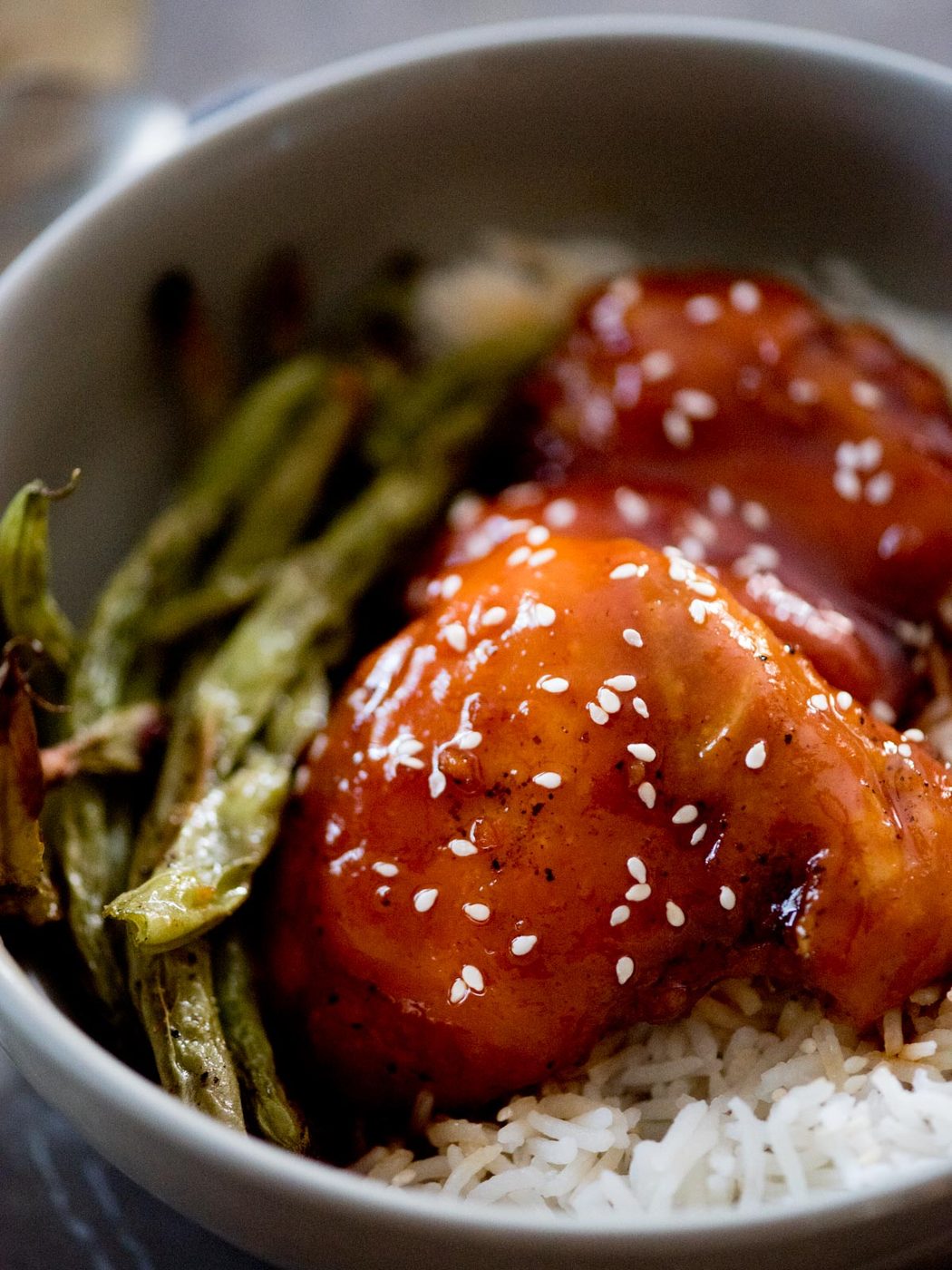 honey garlic chicken topped with sesame seeds over rice and green beans