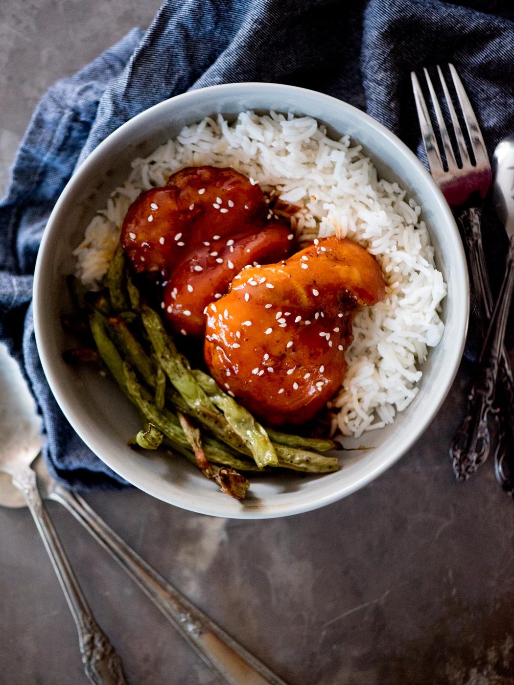 honey garlic chicken topped with sesame seeds over rice and green beans