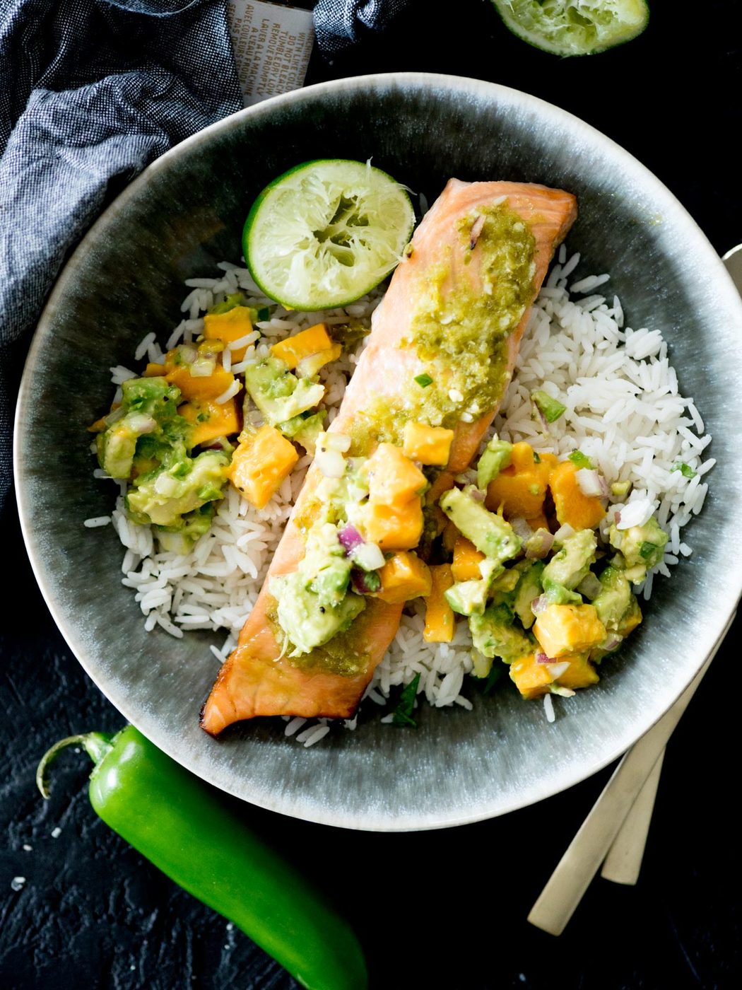 honey jalapeno lime salmon in a bowl with jasmine rice, mango avocado salsa, and a squeezed lime